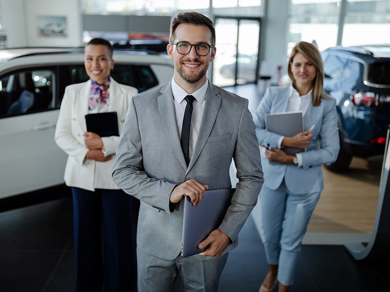 A team is standing in showroom with holding laptop